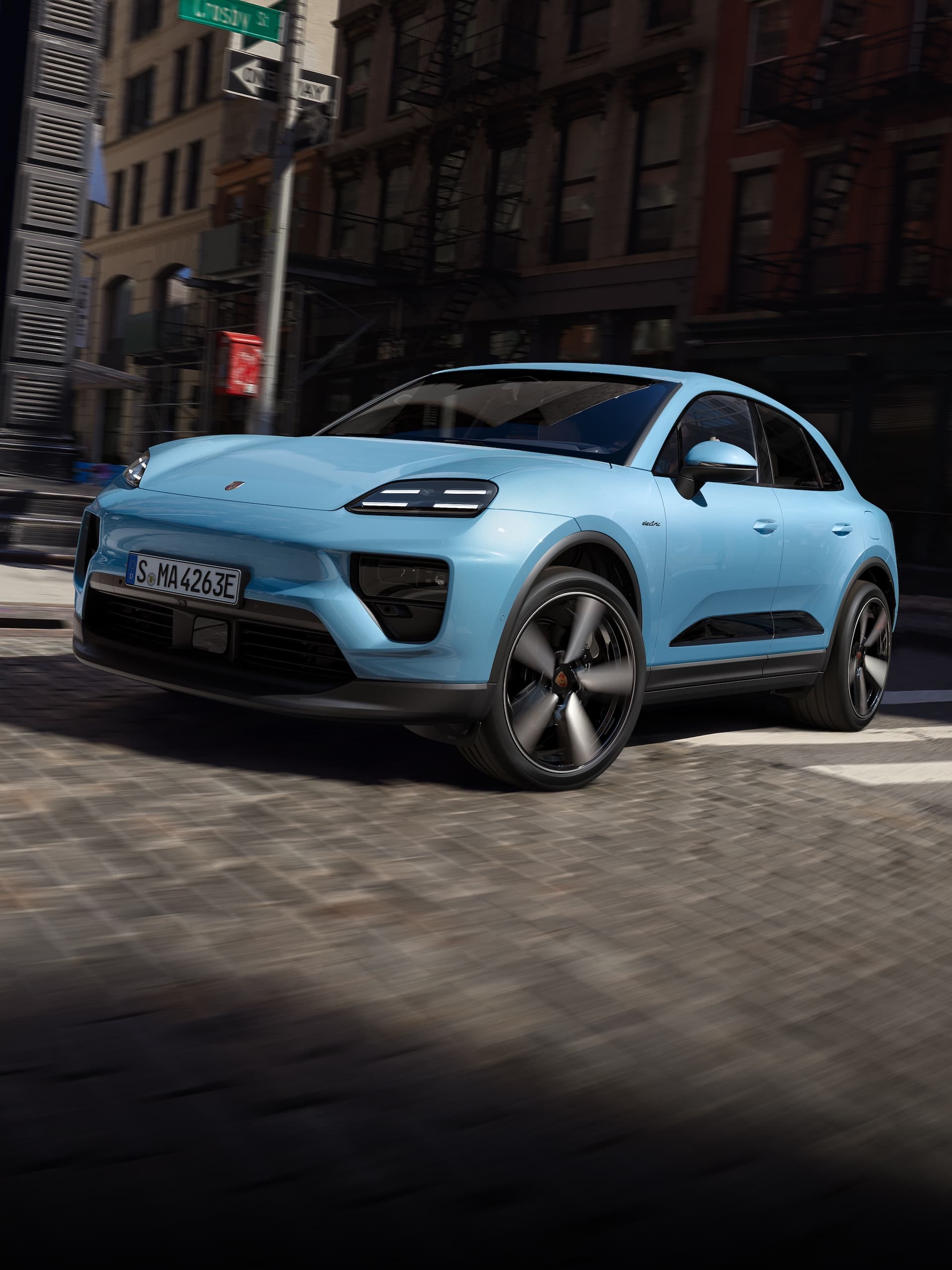 Ein Porsche vollelektrischer Macan, der in einem urbanen Szenario eine Strasse hinunterfährt.
